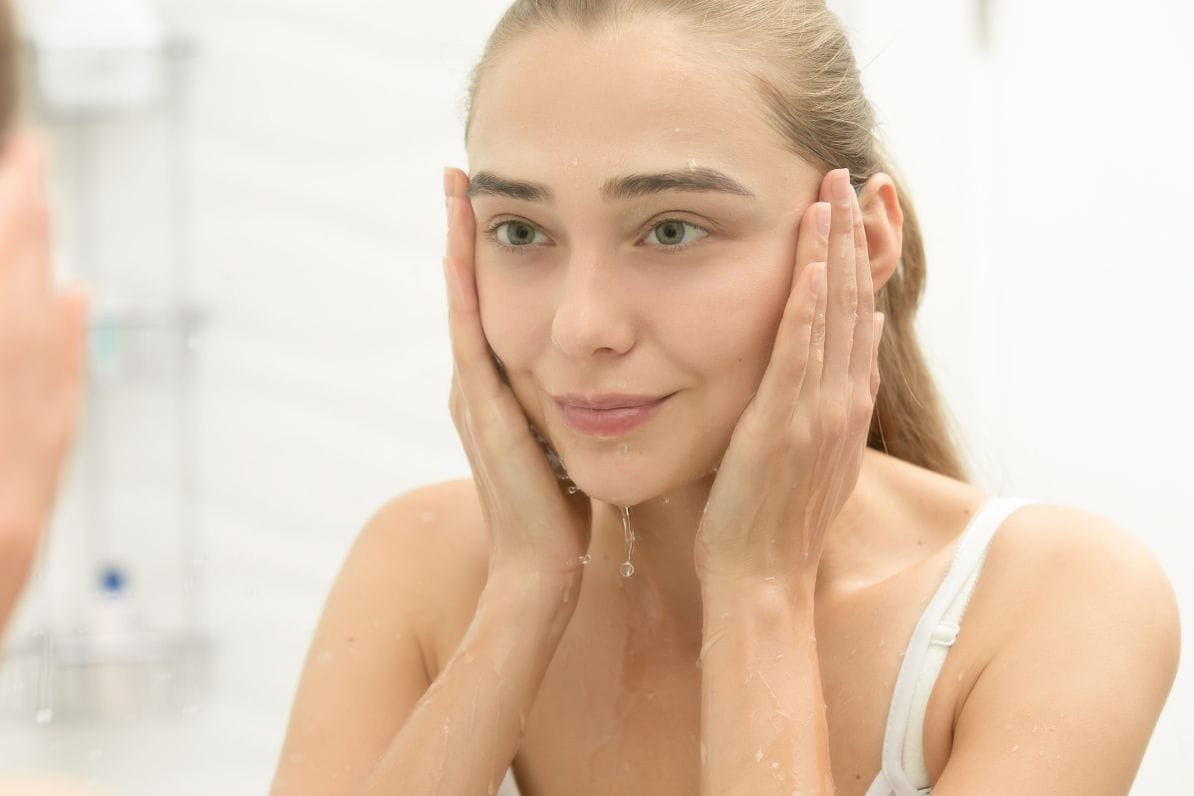 woman smiling in the mirror after profhilo treatment