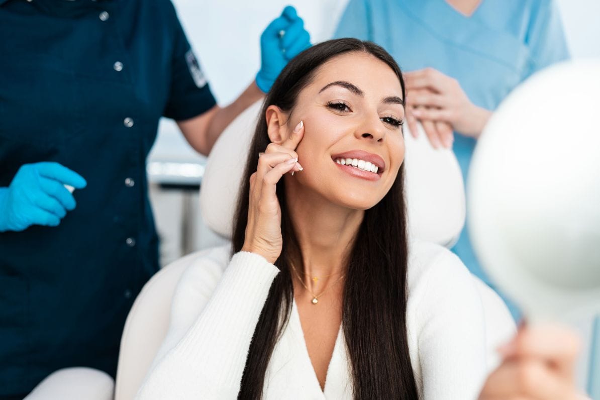 Woman holding up a mirror and smiling after Botox treatment